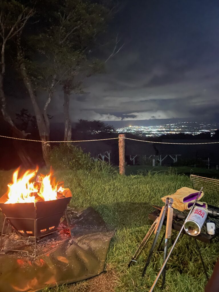 alt="南葉高原キャンプ場で焚火をしながら夜景を眺めている写真"